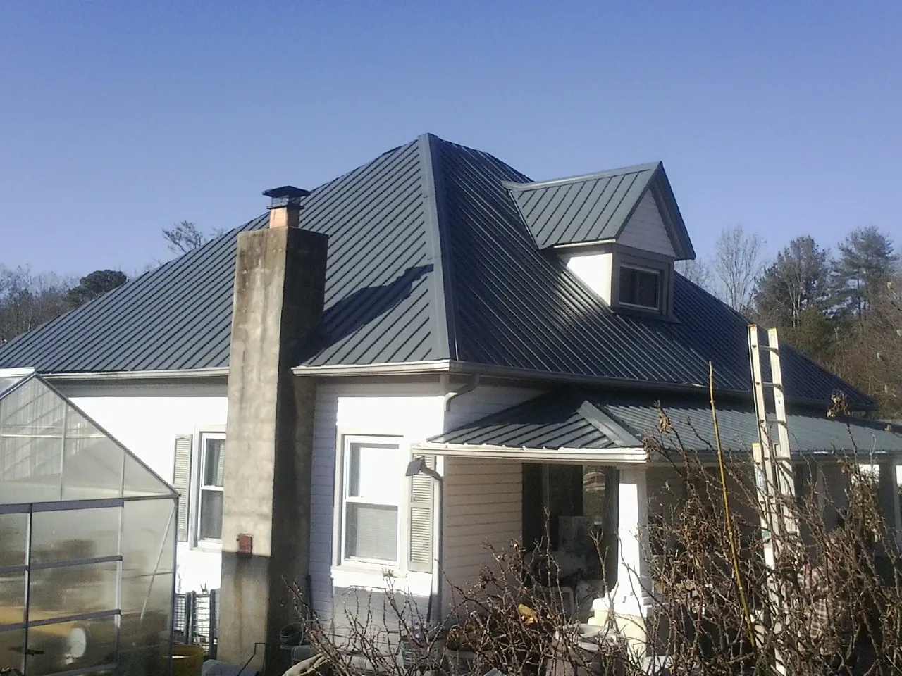 Dark blue standing seam metal roof on a white farmhouse with dormer — Slate & Tile Roof Repair by Roofing Brothers in Briceville