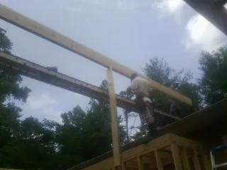 Carpenter setting a ridge beam over a new addition frame — Ice Dam Removal by Roofing Brothers in Briceville
