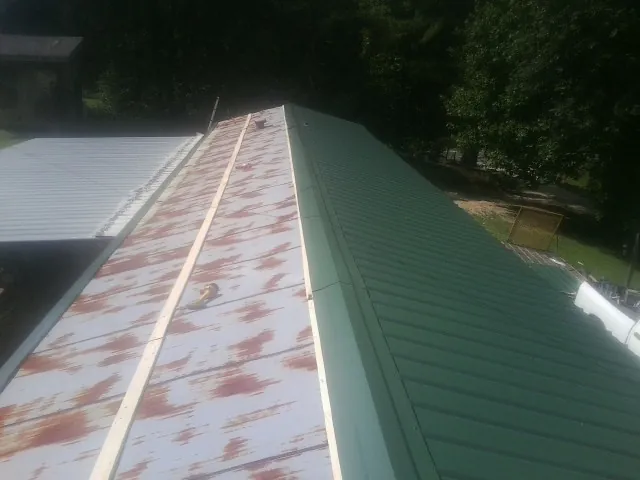 Old rusted panels beside newly installed green metal roofing — Wind Damage Roof Repair by Roofing Brothers in Briceville