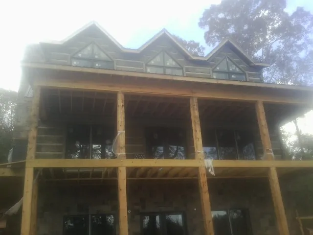 Dormers and porch framing on a large log home under construction — Roof Coating work by our crew in Briceville