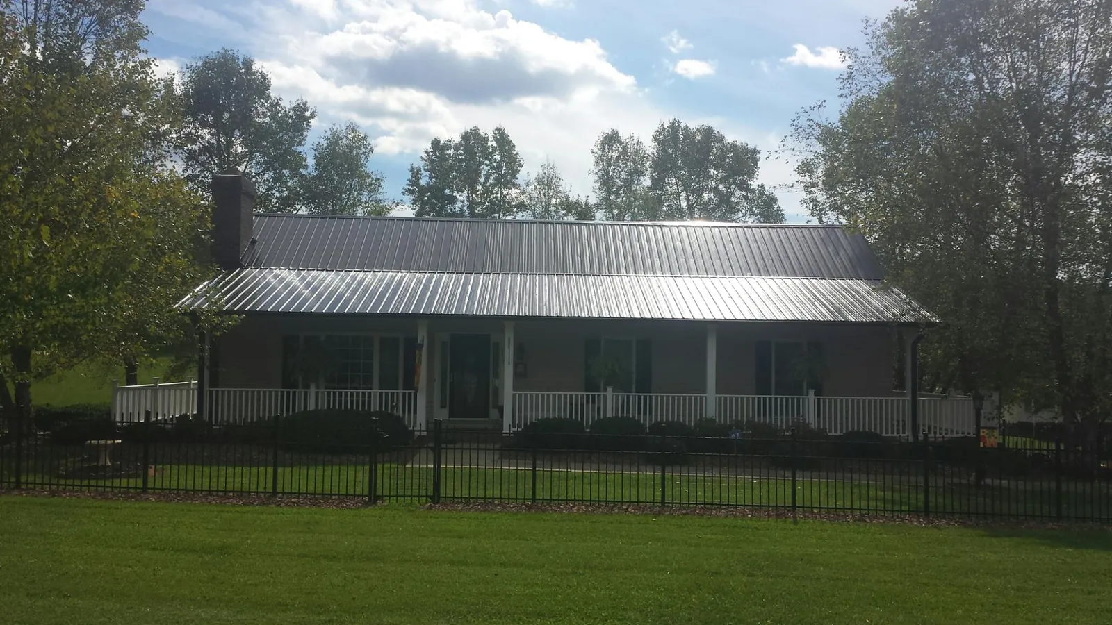 Gray metal roof on a brick ranch with a full width front porch — Gutter Guard Installation work by our crew in Briceville