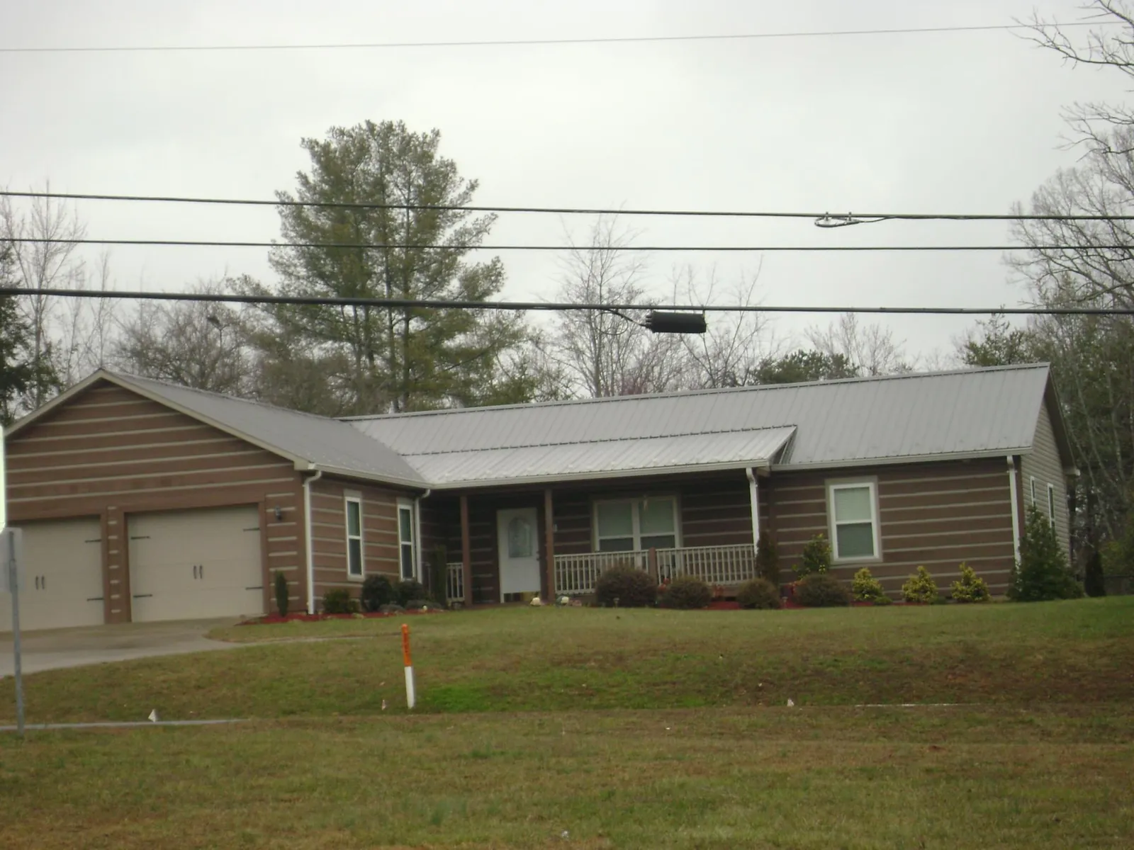 Gray metal roof on a log sided ranch home with a front porch in Briceville