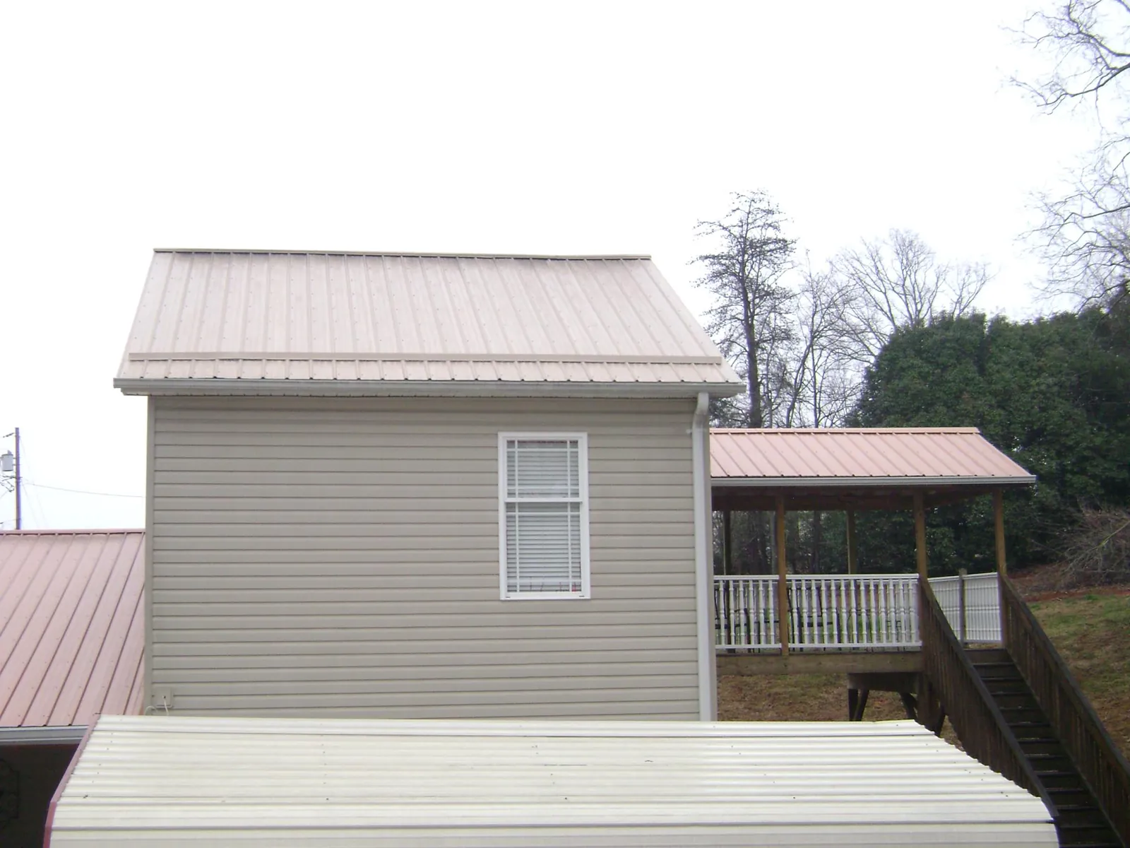 Tan metal roofs on a two story addition and attached porch, from a Roof Replacement job in Briceville